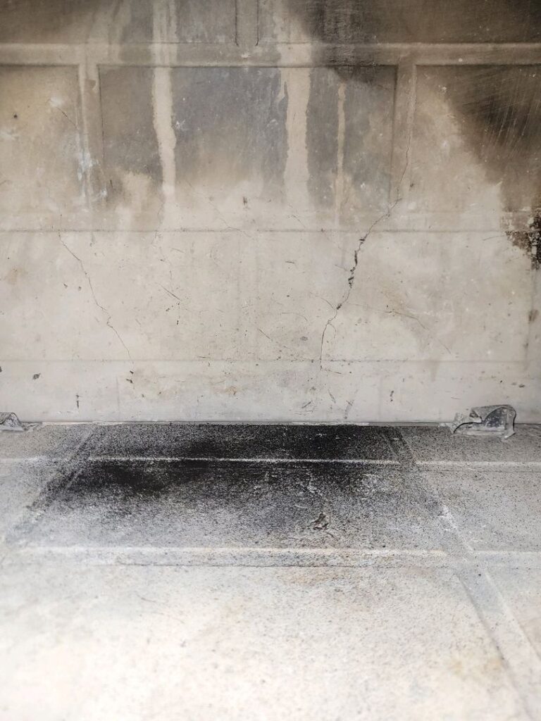 Close-up of a fireplace firebox with a crack in the back wall and soot deposits