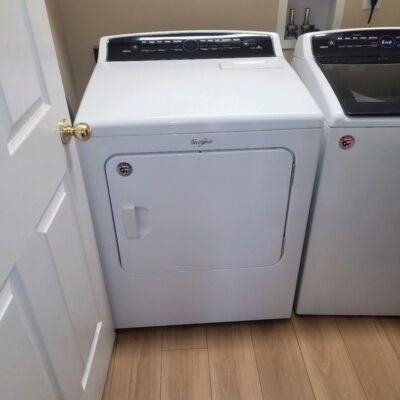 Whirlpool laundry dryer next to a washing machine in a clean laundry room