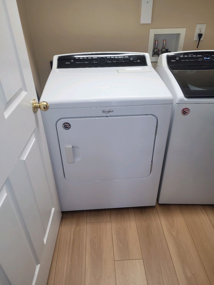 Whirlpool laundry dryer next to a washing machine in a clean laundry room