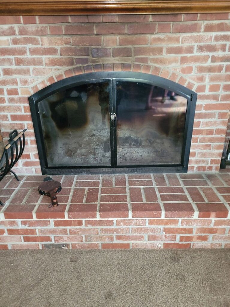 Brick fireplace with a sooty glass door and no visible fire inside