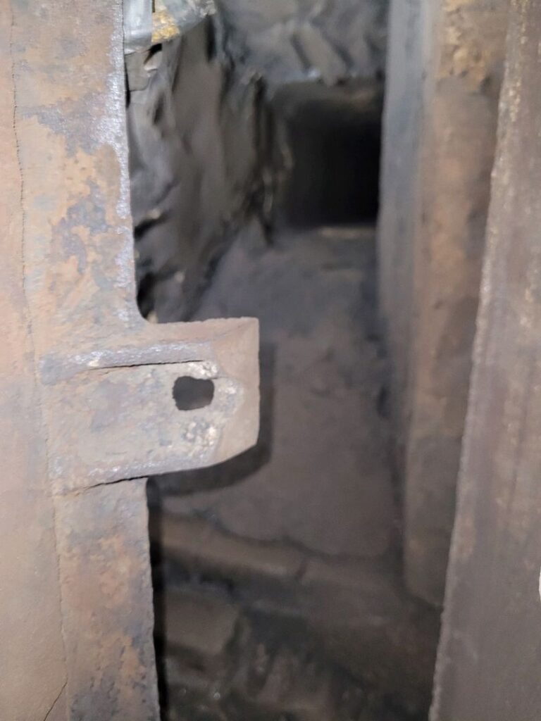 Close-up image of a rusty metal part with a hole against a dark background.