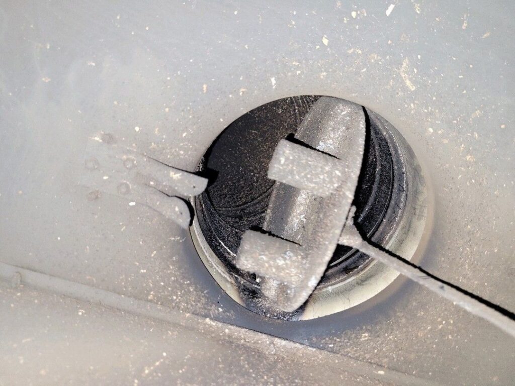 Close-up image of an open black damper inside gray ductwork with visible dust particles.