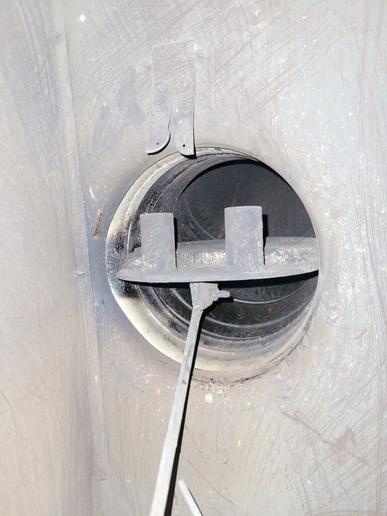 Close-up image of an open chimney damper with soot and signs of wear