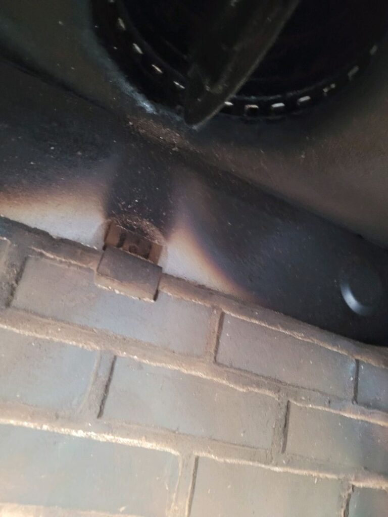 Close-up image of the interior of a firebox with burn marks on bricks and a metal component visible