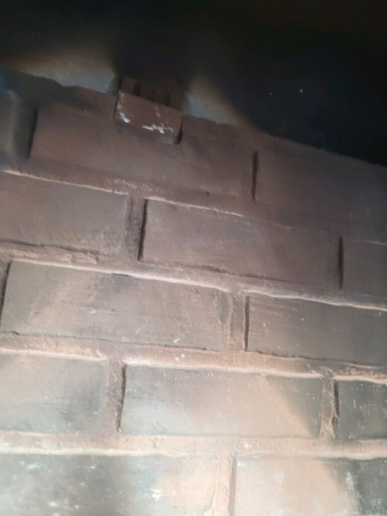 Interior view of a firebox showing damaged and discolored bricks.