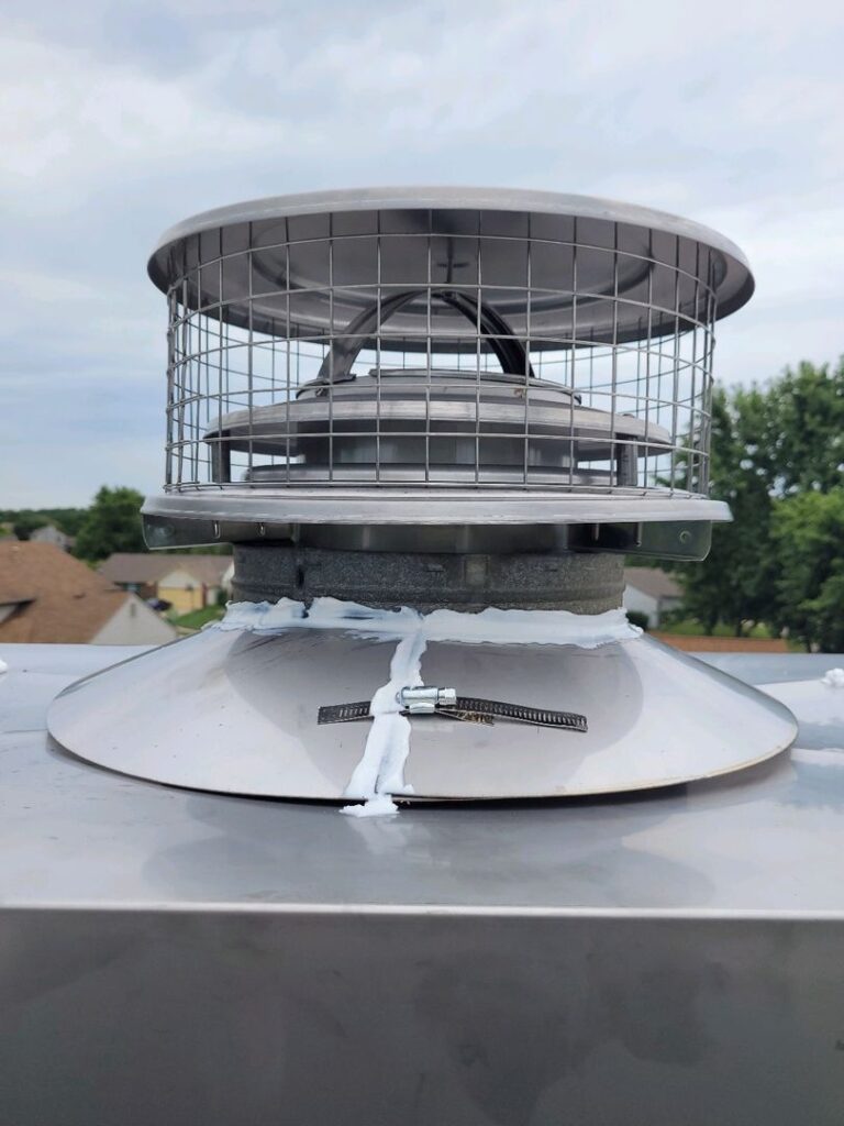 New metal chimney cap with white sealing material on a residential rooftop.